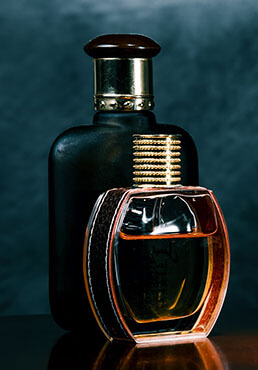 Romantic pair of glass  scent bottles on a dark surface of the noble wood.