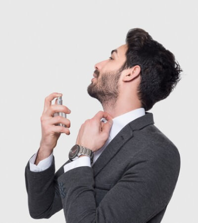 portrait-of-handsome-businessman-in-suit-applying-perfume-over-gray-picture-id930581644