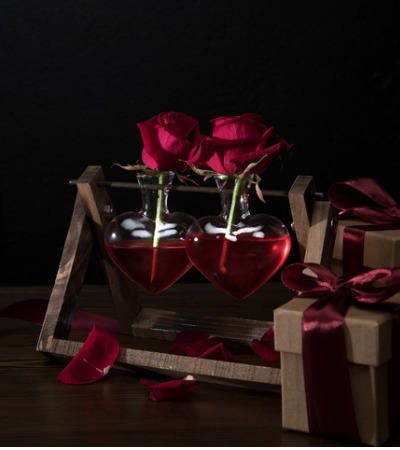 two-red-roses-in-heart-shaped-vases-on-wooden-stand-picture-id905988892